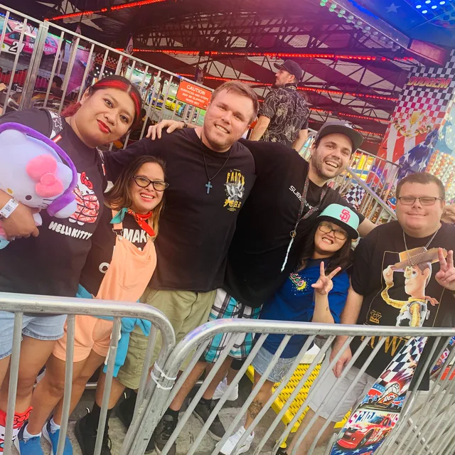 A group of friends with arms around each other outside the bumper cars