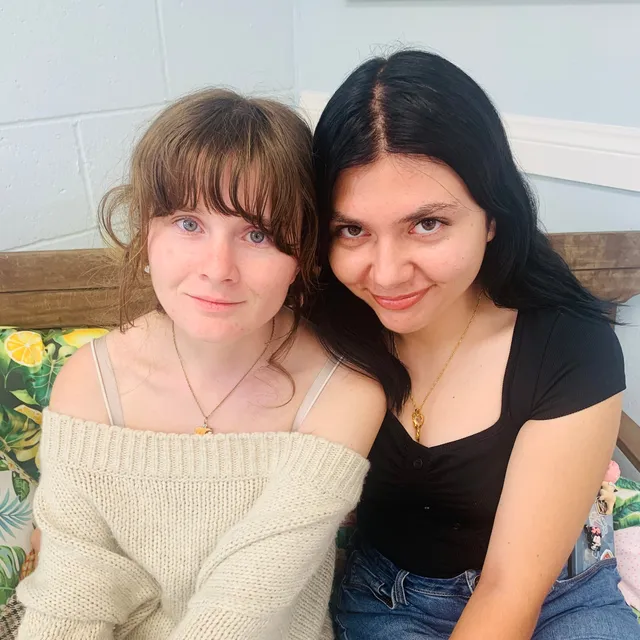 Two young women sitting close together on a bench