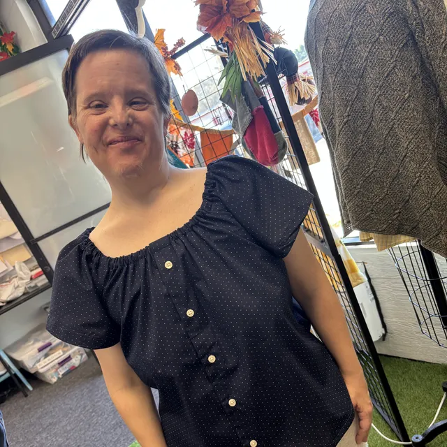 A smiling young woman showing off her new polka-dot blouse