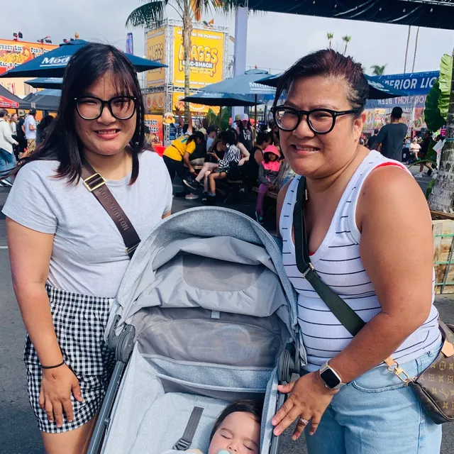 Two friends smiling beside a stroller at the fair