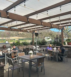 A café patio with tables under a pergola and string lights