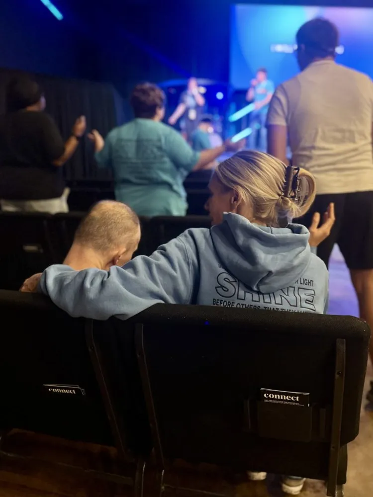 A friend with her arm around another friend during worship