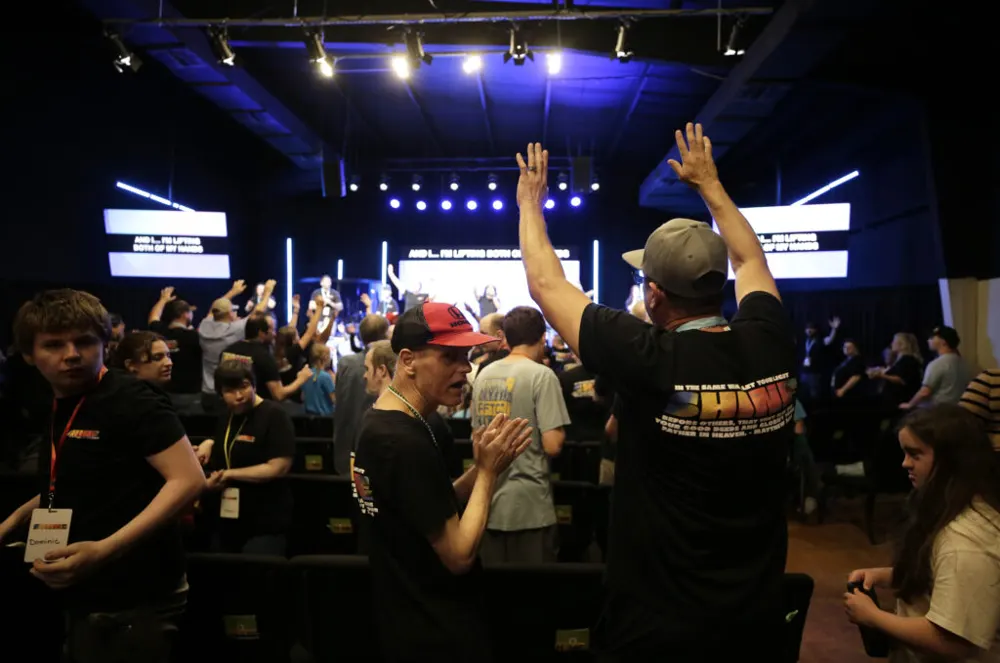 Friends worshipping together with hands raised during a service