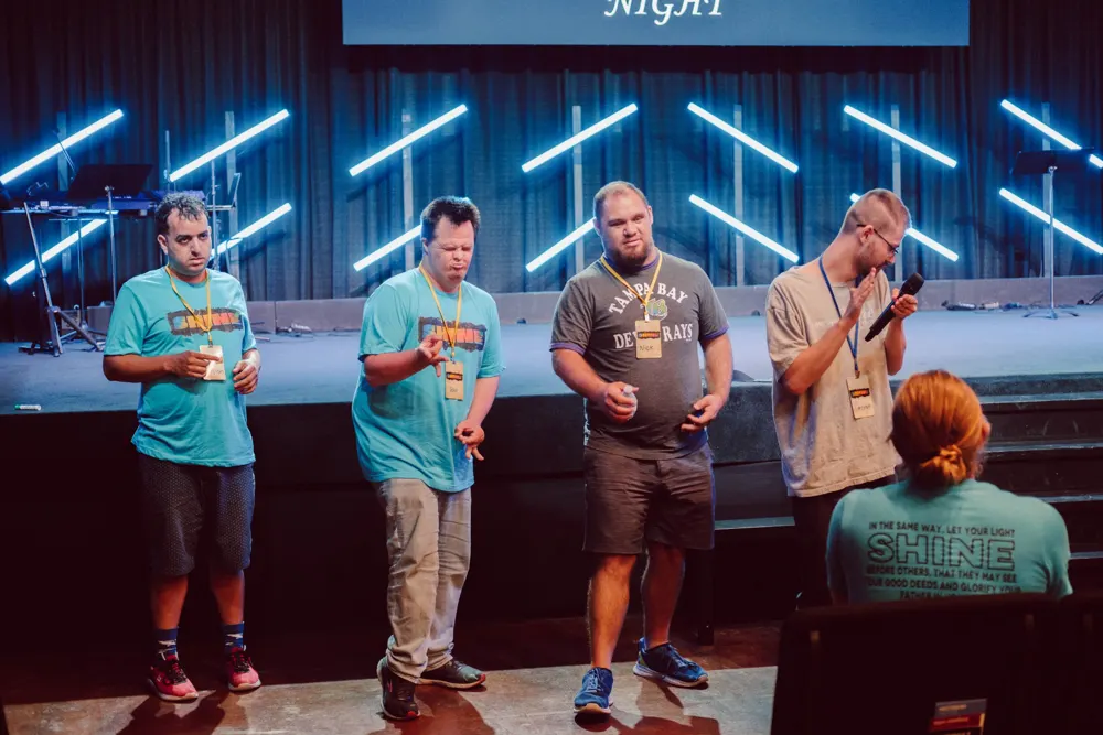 Four friends in front of a stage taking part in a service